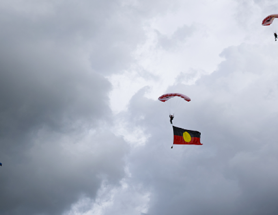 Australian Army soldiers from the Red Berets parachute display team prepare to land at the Bomaderry High School trailing flags as part of an Australian Defence Force Parachuting School visit to the school in Nowra, NSW.